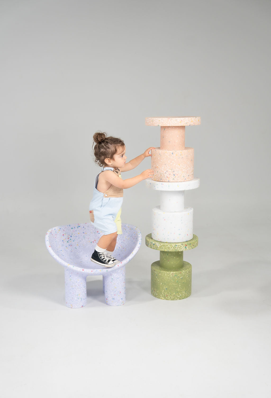 Child standing next to stacked Side tables