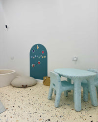 Children's playroom with light blue table and chairs against a white wall.