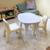 Children's table and chairs set in a playroom with toys and a sofa.