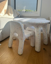 Children's table and chairs in a living room setting with a couch and window in the background.