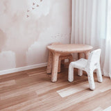 Children's furniture including a small table and chair in a room with light-colored walls and flooring.