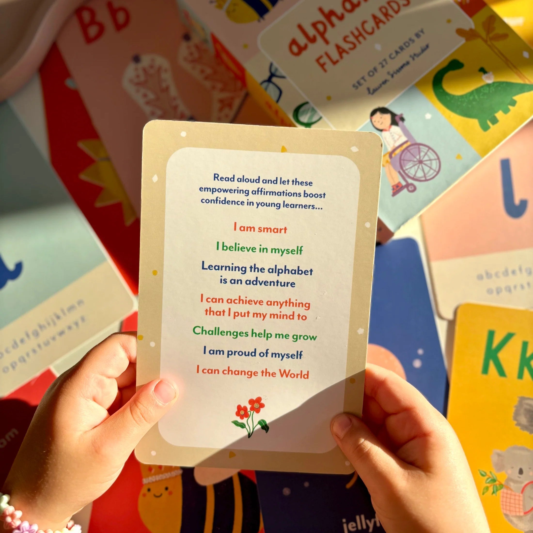 Person holding an alphabet flashcard with affirmations surrounded by more flashcards.