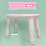 Fairy bread-themed stool with 'Back in Stock!' banner on a light green background
