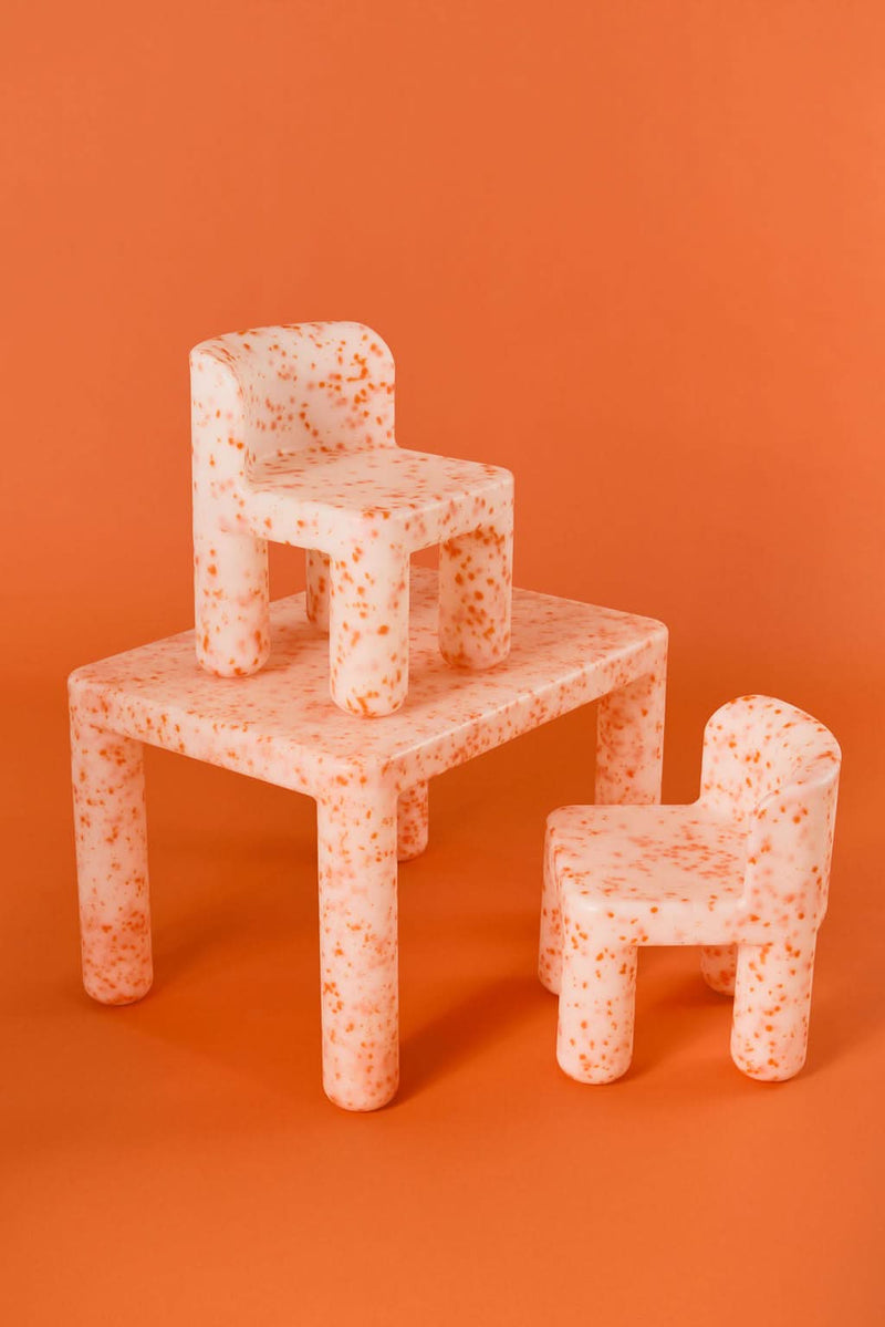 Children's furniture set with table, chairs, and bench on an orange background