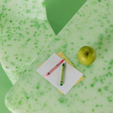 Green textured desk mat with a notebook, pen, and apple on a green background
