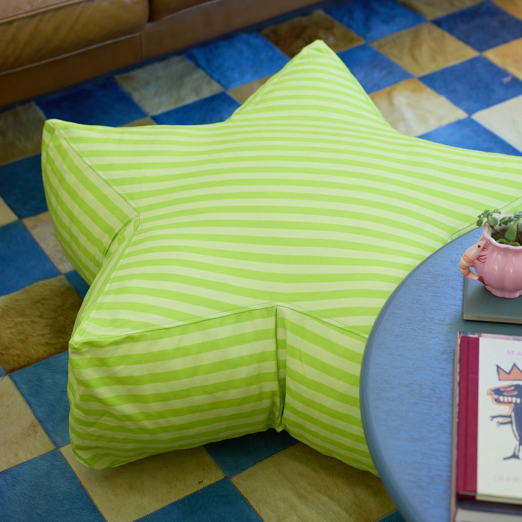 Green striped bean bag chair on a checkered floor with a small table and plant in the foreground.