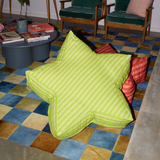 Green striped bean bag chair on a colorful checkered floor with books and chairs in the background.