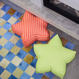 Two star-shaped cushions, one red and one green, on a checkered floor.