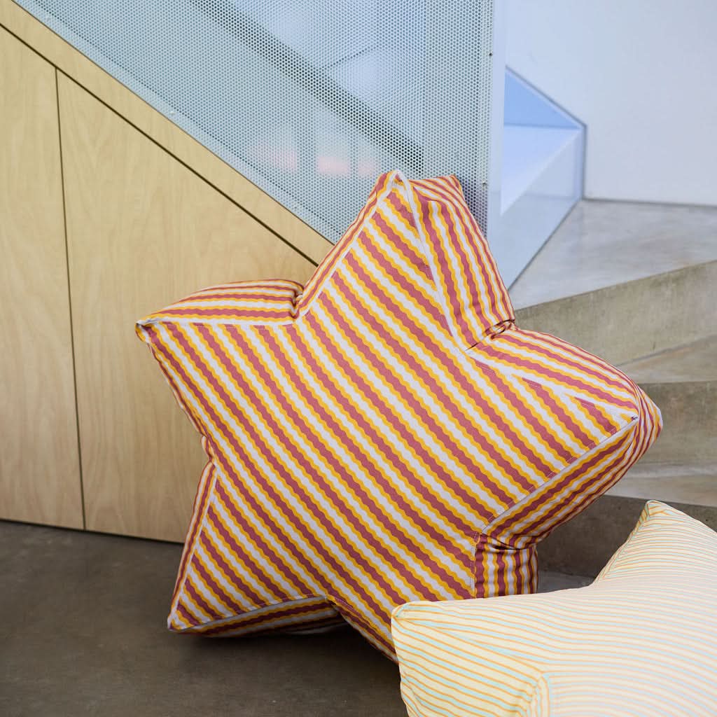 Striped cushions on a concrete floor with a wooden wall and glass panel in the background