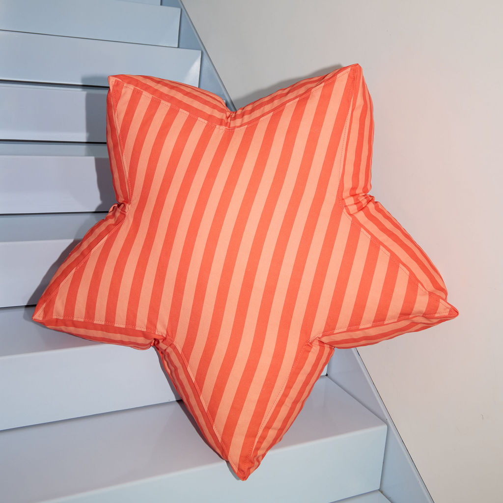 Star-shaped red and pink striped cushion on a staircase