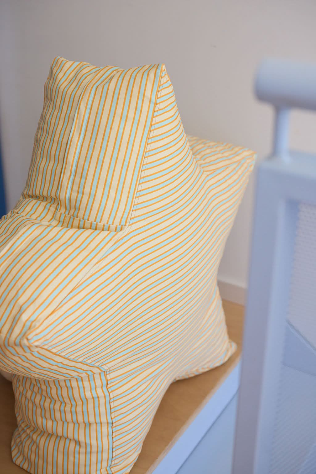 Chair with striped yellow and white cover against a plain wall