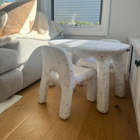 Children's table and chairs in a living room setting with a couch and window in the background.