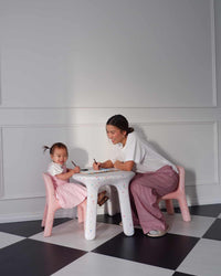 Woman and child sitting at a small table on a checkered floor with white walls.