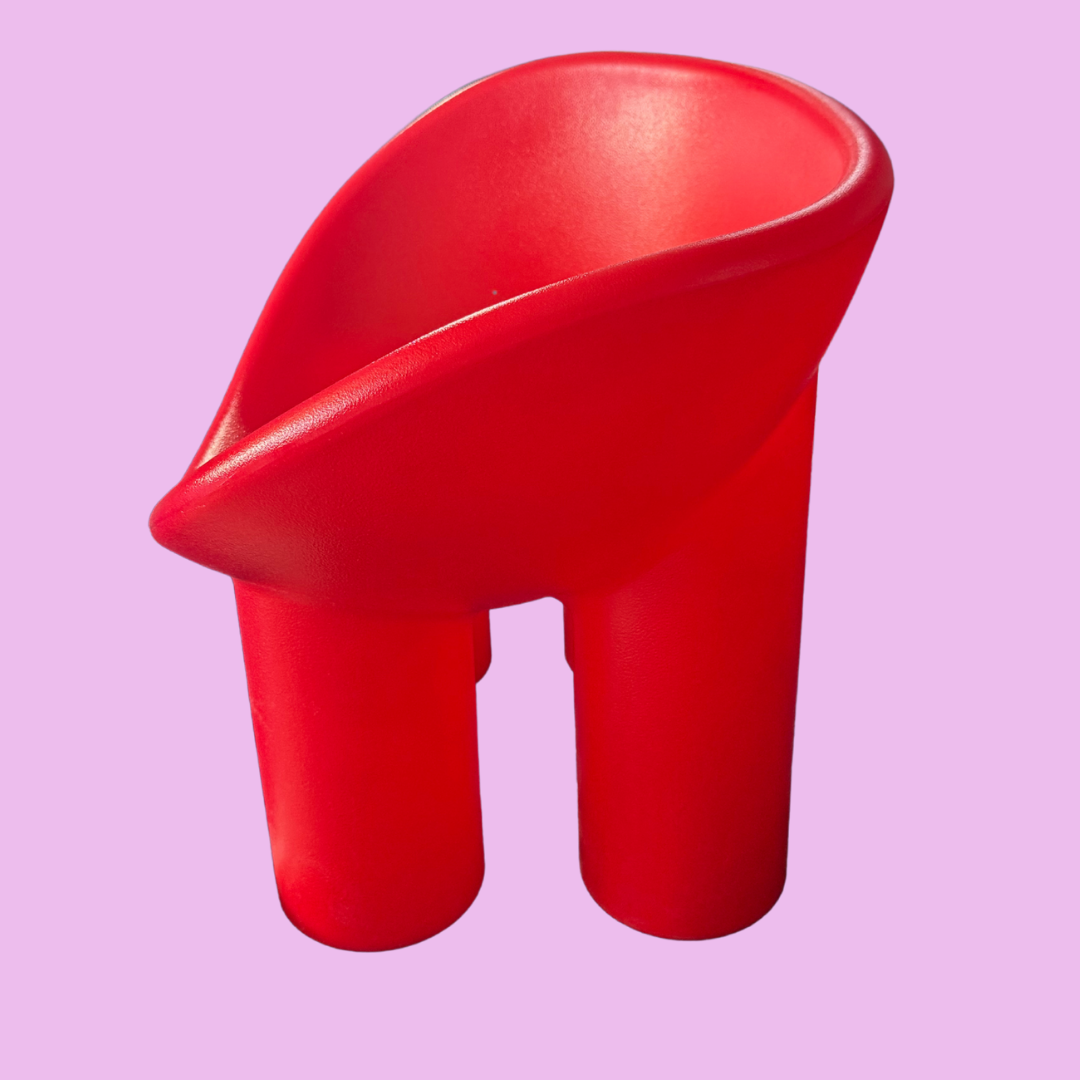 Red plastic chair with a unique design on a pink background, featuring the brand 'Jelly'.