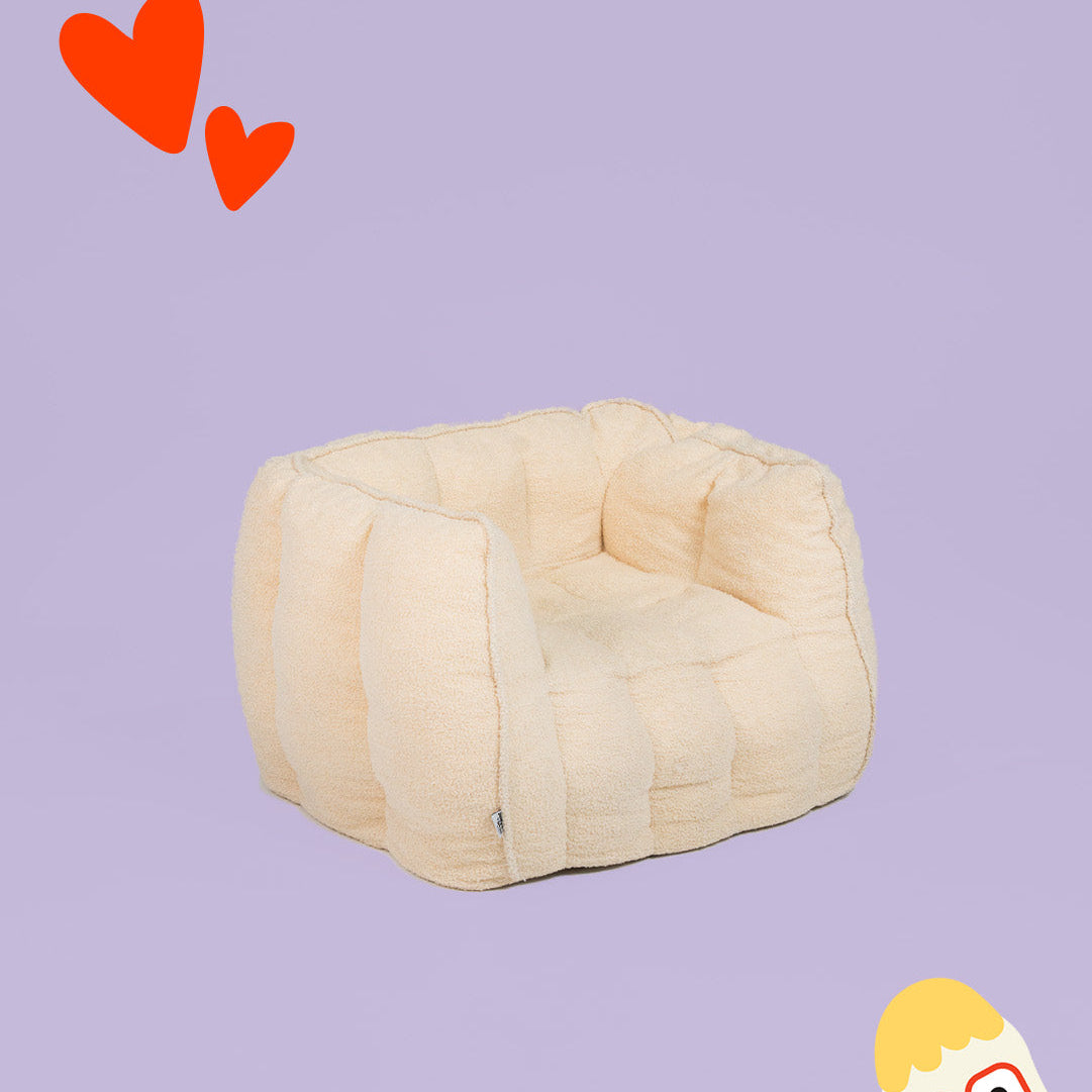 Beige pet bed on a purple background with red hearts and a cartoon character.