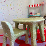 Children's table and chairs in a playroom with colorful walls and toys.