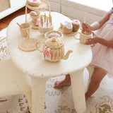 Child playing with a tea set on a small table in a home setting