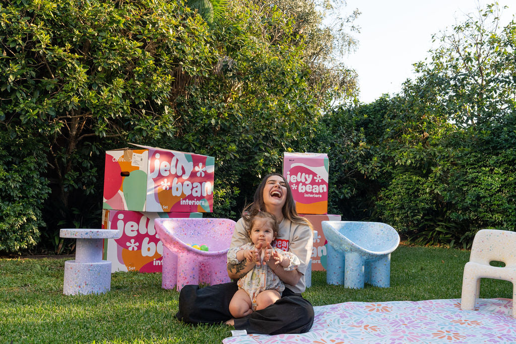 Woman and child sitting on a blanket with Jelly Bean inflatable products in the background
