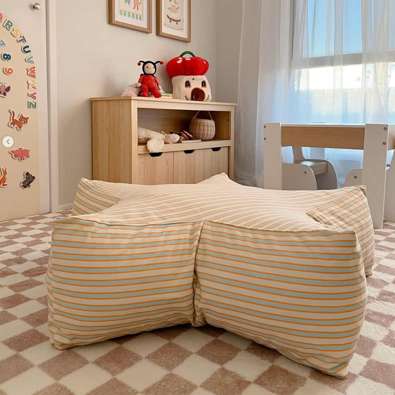 Children's room with striped bed, wooden shelf, and toys.