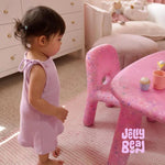 Child in a pink-themed room with a 'Jelly Bean' table