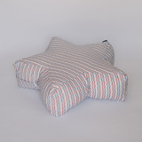 A star-shaped floor cushion with a white base and thin red and blue wavy stripes, photographed against a plain light gray background.