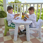 Two children playing with toys at a small table on a patio.