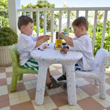Two children playing with toys at a small table on a patio.