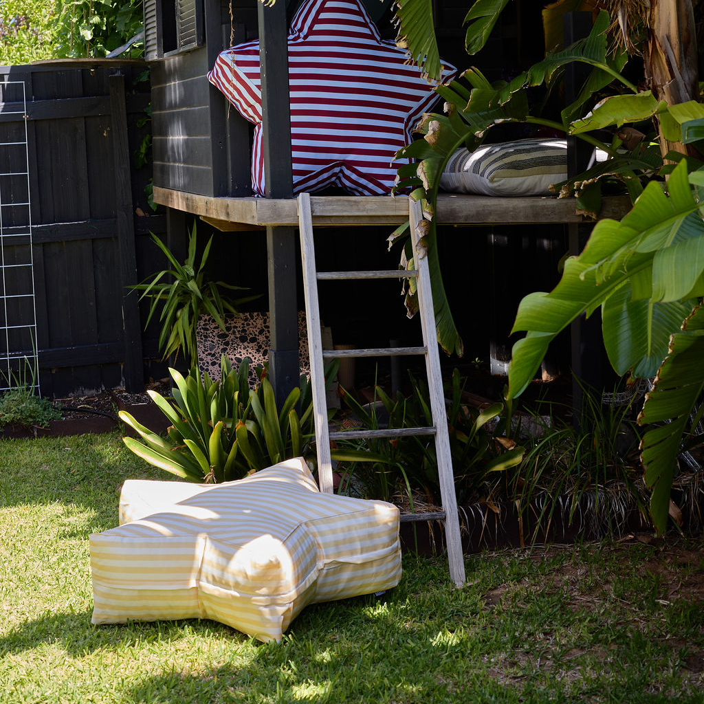 Outdoor setting with striped chair, table, and ottoman on grass